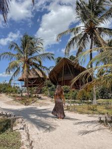 普雷亚Villa Sabiá - Eco Bungalows的一个小女孩在棕榈树海滩上散步