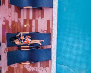 丹格迪Ari Grand Hotel & Spa的躺在游泳池旁椅子上的女人