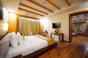 库姆巴科纳姆维哈品质酒店的卧室配有一张白色大床和电视。