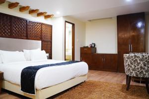 库姆巴科纳姆维哈品质酒店的卧室配有1张床、1张桌子和1把椅子