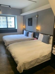 台中市一中自在居的配有白色床单的酒店客房内的两张床