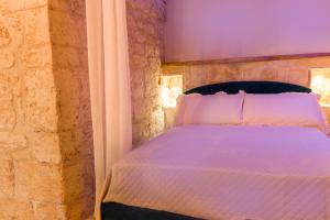 切列梅萨皮卡La Casedda - Apartment & Hydromassage的卧室配有白色的床铺和石墙
