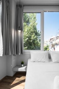 塞萨洛尼基WallStreet, The Luxury Suites的卧室配有白色的床和窗户。