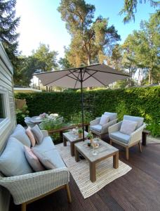 洪德洛Luxe Chalet met prachtig terras op de Veluwe , veel privacy的天井配有沙发和带雨伞的桌子。