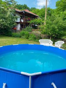 YakovtsiВила Любима的蓝色的游泳池,带两把椅子和房子