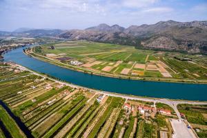 OpuzenApartments with a parking space Opuzen, Neretva Delta - Usce Neretve - 18070的享有河流的空中景色,以山脉为背景