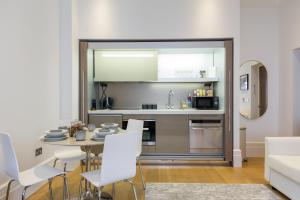 伦敦The Dorset Suite - Stylish New 1 Bedroom Apartment In Marylebone的厨房以及带桌子和白色椅子的用餐室。