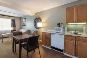 奥本Quality Inn & Suites的厨房以及带桌子和微波炉的客厅。