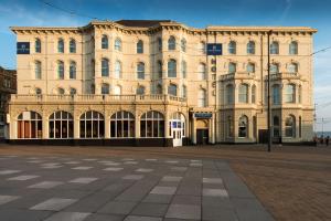 布莱克浦Forshaws Hotel - Blackpool的一座大型的棕褐色建筑,前面有一个广场