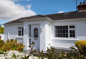 邓甘嫩Rose Haven private home between Dungannon & Omagh的白色的房子,有白色的门和灌木丛