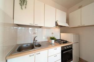 马尔恰纳Da Angiolina的厨房配有白色橱柜、水槽和炉灶。