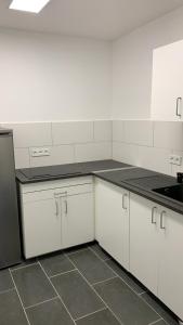 科隆FeWo Hostel的厨房配有白色橱柜和黑色台面