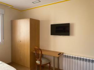 庞特维德拉PENSIÓN SANTA CLARA的一间卧室配有一张桌子和一台墙上的电视。
