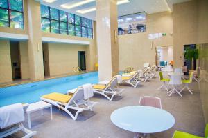 阿比让Hôtel FAMILLE MONDIALE的一个带躺椅和桌子的游泳池以及游泳池