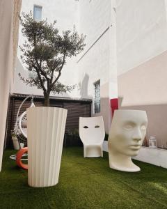 皮亚琴察Casa Del Profumo的两座白雕塑,坐在一座建筑前面的草上