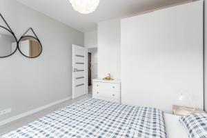 华沙Chill Apartments Ursus的白色卧室配有蓝色和白色的格子床