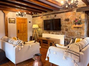 Cilleruelo de BezanaCasa Rural Puerto del Escudo的客厅配有两把白色椅子和电视