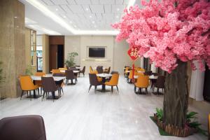 阿比让Hôtel FAMILLE MONDIALE的一间设有桌椅的餐厅,以及一棵种有粉红色花卉的树