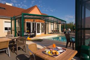 圣吉尔密斯Logis Jum'Hotel的一个带桌椅的庭院和一个游泳池