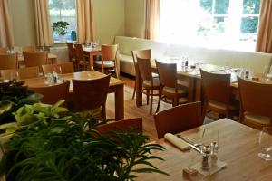 扎布热赫波兹诺夫康体酒店的餐厅设有木桌和椅子,种有植物