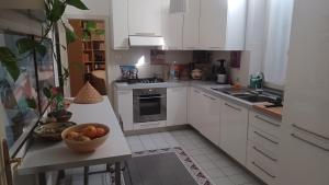 摩德纳Casa Braglia的厨房配有白色橱柜和柜台上的一碗水果