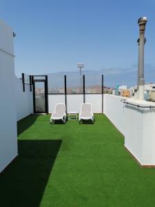 阿里纳加Apartamentos Risco Verde的阳台配有两把椅子和绿草