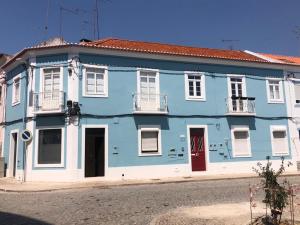 萨尔堡Casa do Mercado的蓝色的建筑,有白色的窗户和红色的门