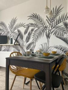 库尔瑟勒·苏尔·梅尔Appt centre de Courseulles - 100m de la plage的餐桌、椅子和棕榈树壁画