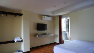 清迈Airport A1 Hotel的一间卧室设有一张床、一台电视和一个窗口。