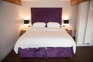 大德里菲尔德四十一号酒店的一间卧室配有一张大床和紫色床头板