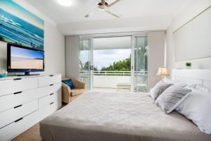 阳光海岸Unit 4 Cote DAzur 6 Douglas Street Sunshine Beach的一间卧室配有一张大床和电视