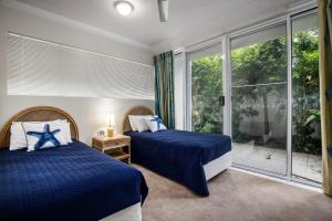 阳光海岸Unit 4 Cote DAzur 6 Douglas Street Sunshine Beach的一间卧室设有两张床和大窗户