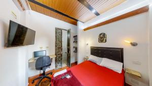 麦德林Casa Los Naranjos Hostal的一间卧室配有红色的床和一台平面电视