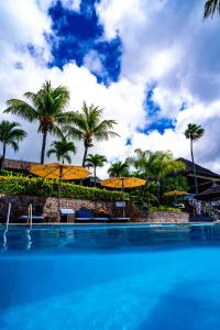 贝尔欧布莱Fisherman's Cove Resort的一个带黄色遮阳伞和棕榈树的游泳池