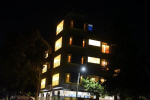 迈索尔The Vihar service Apartment的一座高大的建筑,晚上有窗户照亮