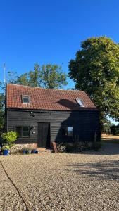 DepdenGorgeous comfortable barn with huge private orchard in quiet Suffolk location的大型黑色谷仓,有红色屋顶