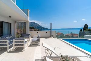 奥米什Luxurious VILLA LAPIS - heated pool, sauna, gym and spa, 120m to sandy beach的一个带椅子的庭院和一个游泳池