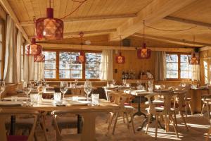 阿罗萨Alpenblick Bergrestaurant & Hotel的餐厅设有木桌、椅子和窗户。
