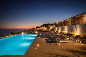 ValeriánosKefalonian Escape Suites的一个带躺椅的游泳池,晚上则享有海景