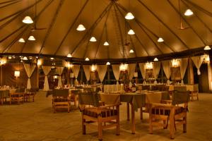 塔勒克Mara Maisha Camp的一个带桌椅和灯的大型帐篷