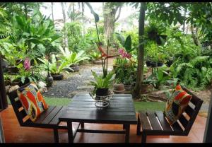 普吉镇用餐及住宿公寓的花园里种有植物,配有木桌和椅子
