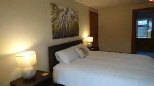 恩尼斯基林Rossclare Lodge的卧室配有白色的床和两盏灯。