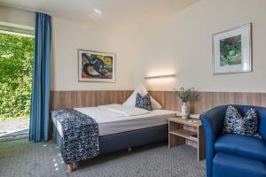 慕尼黑艾玛慕斯菲尔德酒店的酒店客房,配有一张床和一张蓝色椅子