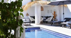 迦玛特VILLA EDO的游泳池配有椅子、遮阳伞和桌子