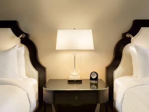 温哥华Fairmont Hotel Vancouver的客房设有两张床和一张带时钟的桌子。