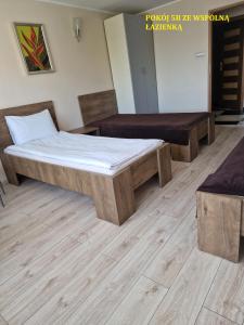 比得哥什Centrum Noclegowe II的铺有木地板的客房内的一张床铺和长凳