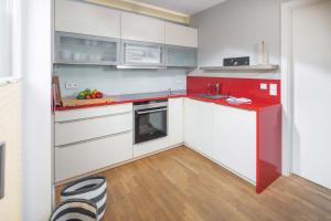 诺德奈Mühlenloft的厨房配有白色橱柜和红色台面