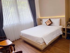 邦美蜀Thanh Bình Hotel - 47 Y Bih - BMT的一间卧室配有一张带白色床单的床和一扇窗户。