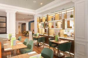 吉尔福德假日吉尔福德酒店的餐厅设有木桌和绿色椅子