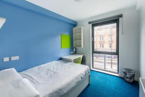 爱丁堡舒希尔学生之家旅舍（校园住宿）的蓝色的卧室设有床和窗户